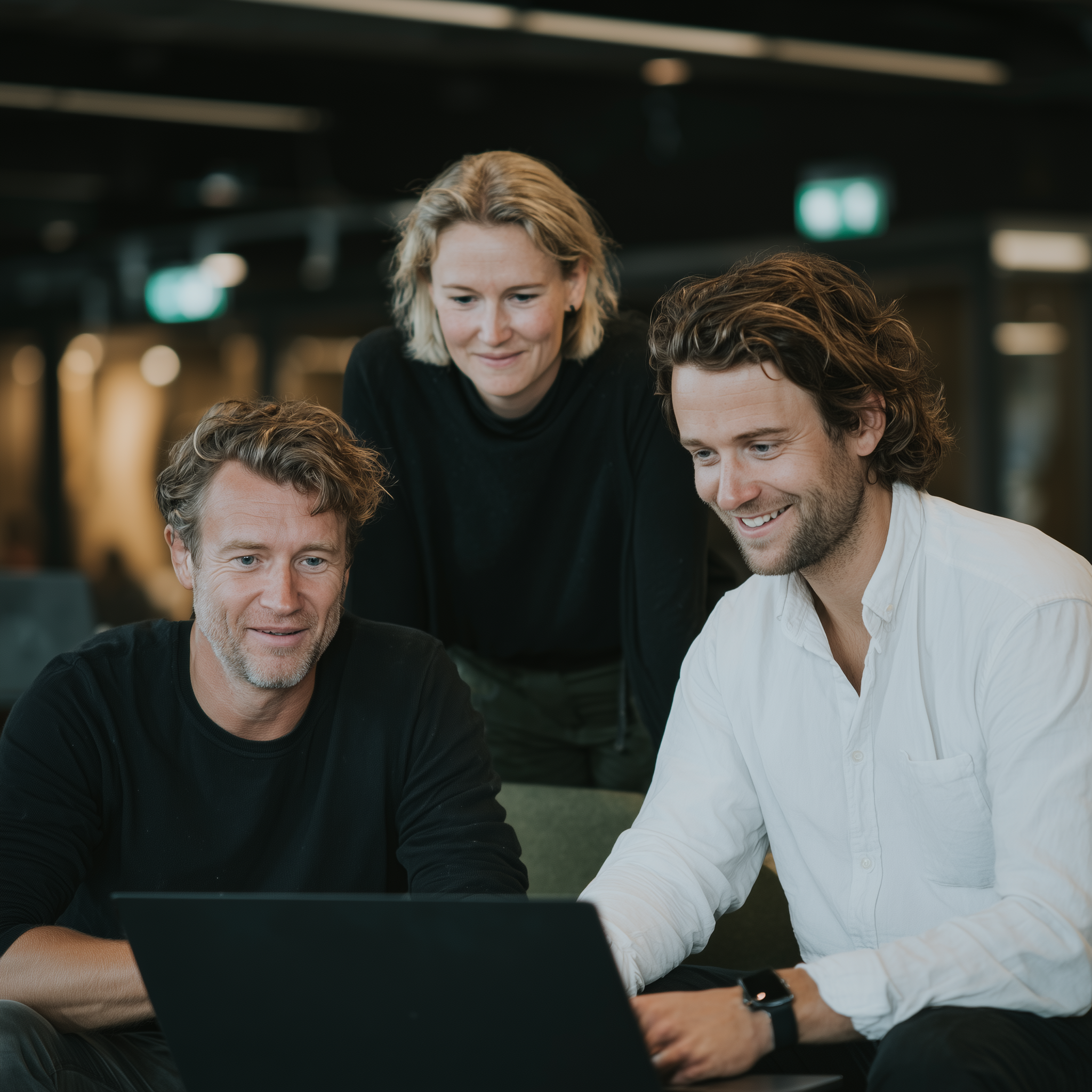 Three colleagues sharing ideas around a laptop